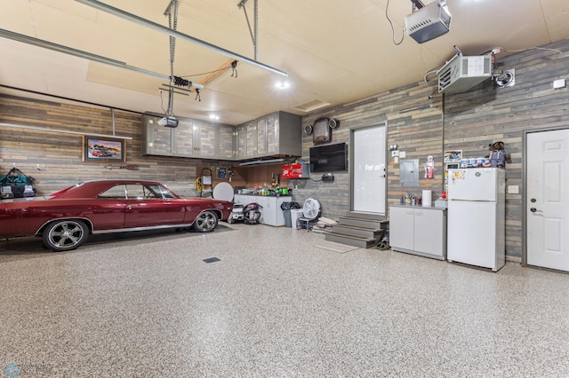 garage featuring a garage door opener, white refrigerator, and wooden walls