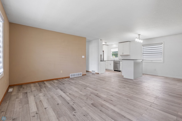 unfurnished living room with light hardwood / wood-style floors and a chandelier