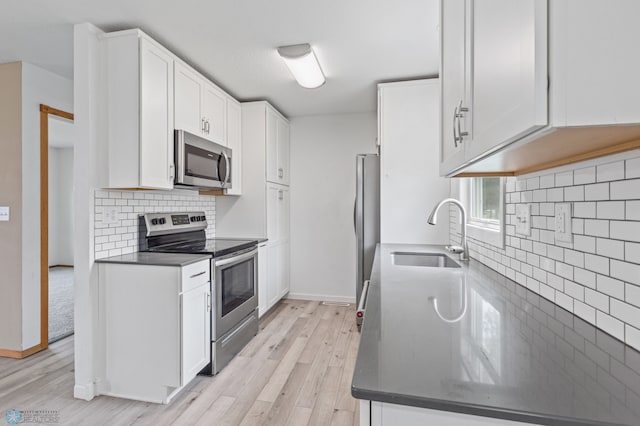 kitchen with stainless steel appliances, sink, decorative backsplash, light wood-type flooring, and white cabinetry