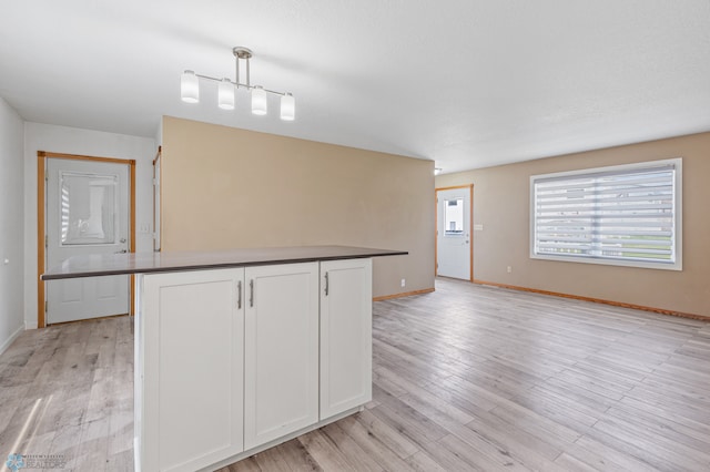 kitchen featuring white cabinetry, light hardwood / wood-style flooring, and pendant lighting