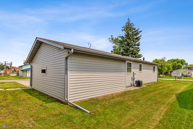 view of side of home with central air condition unit and a yard