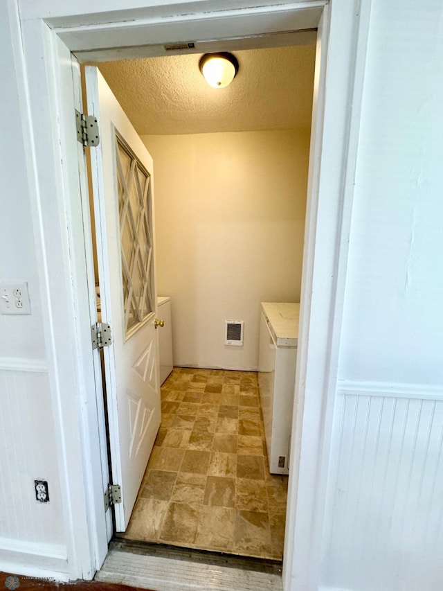 clothes washing area featuring light tile patterned floors and a textured ceiling