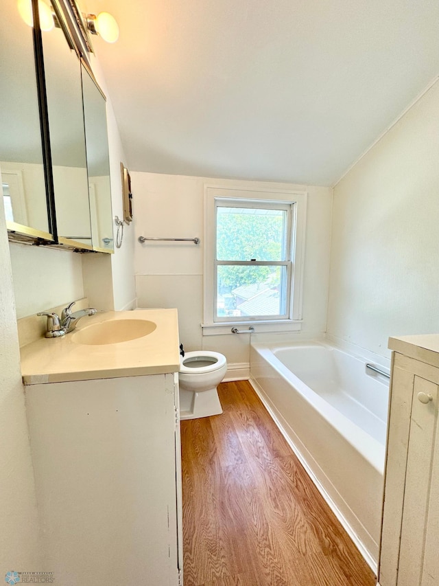 bathroom featuring a tub, wood-type flooring, vanity, and toilet