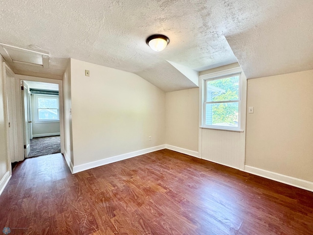 additional living space with hardwood / wood-style floors, a textured ceiling, and vaulted ceiling