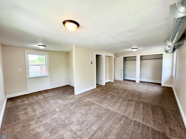 unfurnished bedroom featuring two closets, carpet, and a textured ceiling