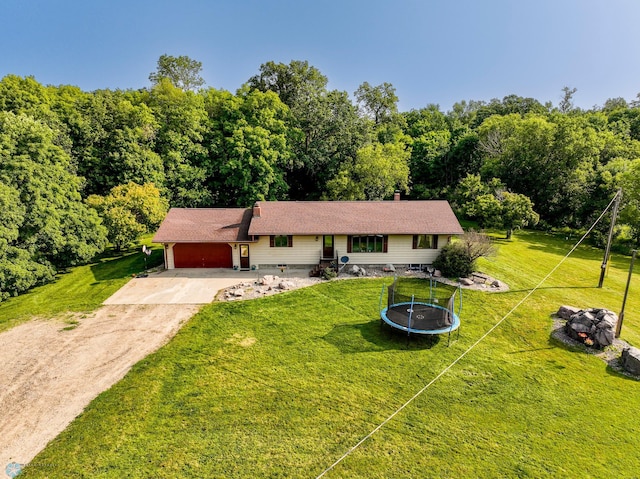 ranch-style house with a front yard, a trampoline, and a garage