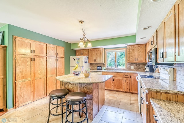 kitchen featuring white appliances, a kitchen bar, backsplash, a center island, and pendant lighting