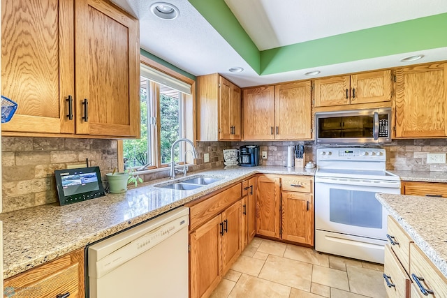 kitchen with tasteful backsplash, light stone counters, light tile patterned floors, sink, and white appliances