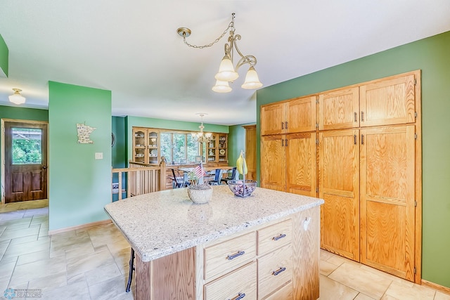 kitchen featuring light stone counters, a breakfast bar, a chandelier, pendant lighting, and a center island