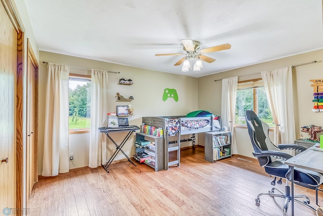 bedroom with ceiling fan, wood-type flooring, and multiple windows