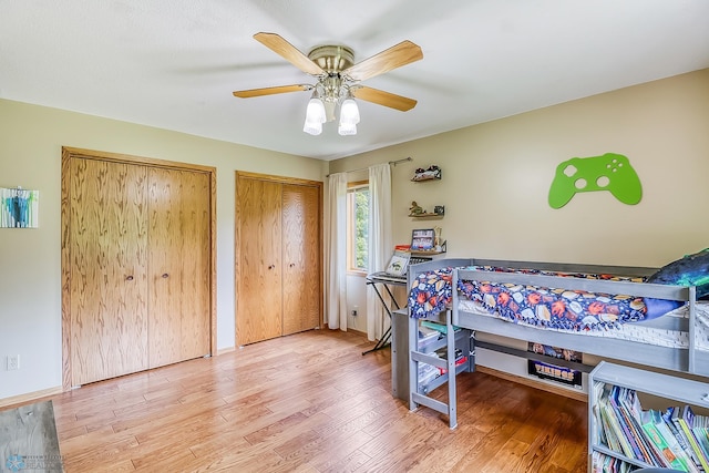 bedroom featuring hardwood / wood-style floors, two closets, and ceiling fan