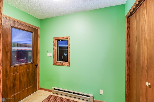 entryway with baseboard heating, a textured ceiling, and light tile patterned floors