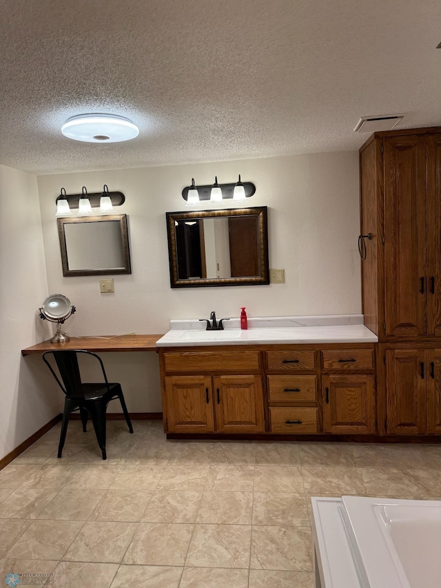 bathroom with vanity, a textured ceiling, and a tub to relax in