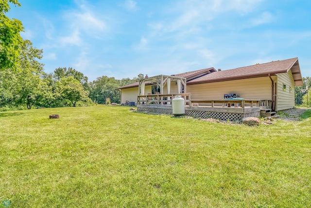 rear view of property featuring a wooden deck and a lawn