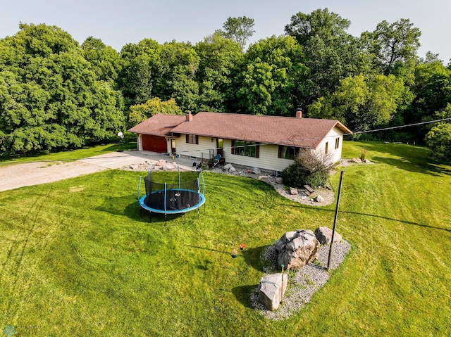 ranch-style home with a front lawn, a trampoline, and a garage