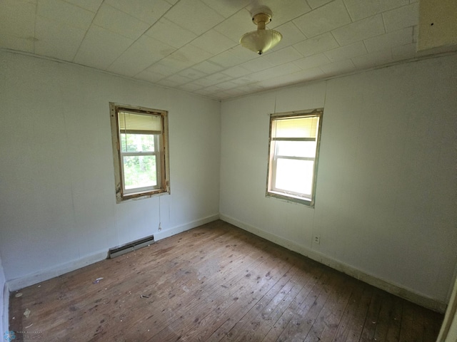 unfurnished room with a baseboard heating unit and hardwood / wood-style floors