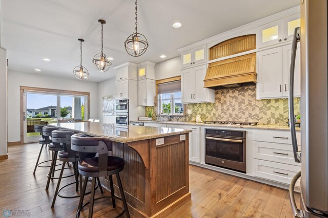 kitchen featuring white cabinetry, a center island, custom exhaust hood, and light hardwood / wood-style flooring