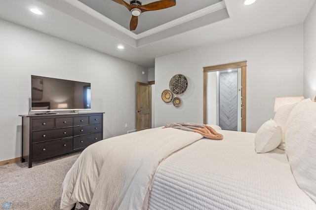 carpeted bedroom with ceiling fan, ensuite bath, and a tray ceiling