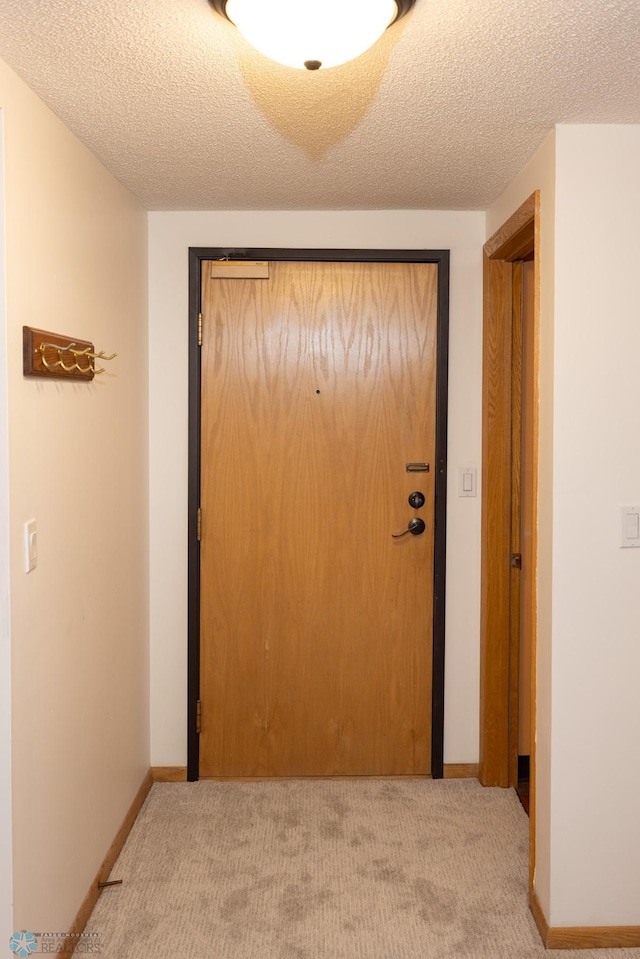 hallway with light carpet and a textured ceiling