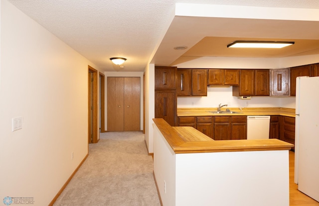 kitchen featuring white appliances, light carpet, a textured ceiling, and sink