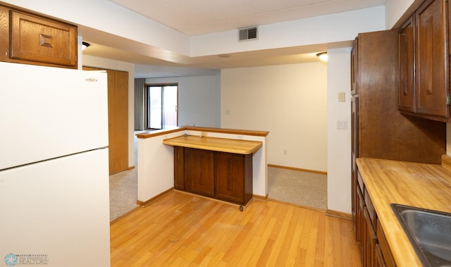 kitchen featuring white fridge, wood counters, light hardwood / wood-style flooring, and sink