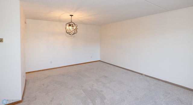 carpeted spare room featuring an inviting chandelier