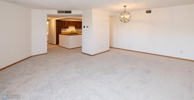 carpeted spare room with an inviting chandelier