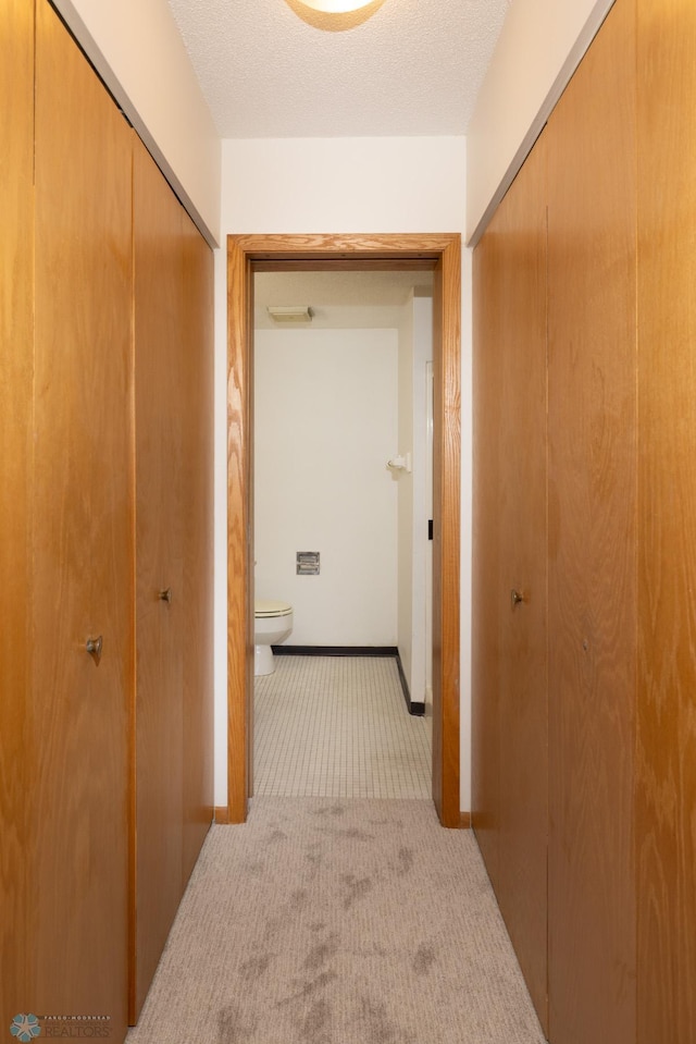 hall with light carpet and a textured ceiling