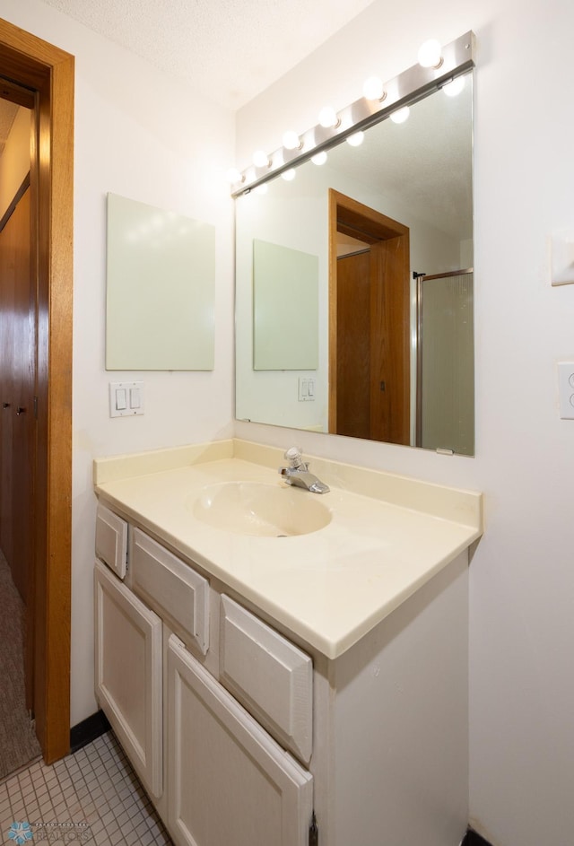 bathroom with vanity, tile patterned floors, a textured ceiling, and walk in shower