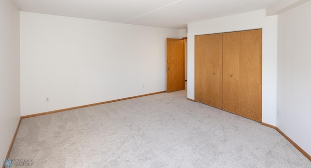 unfurnished bedroom featuring light carpet and a closet