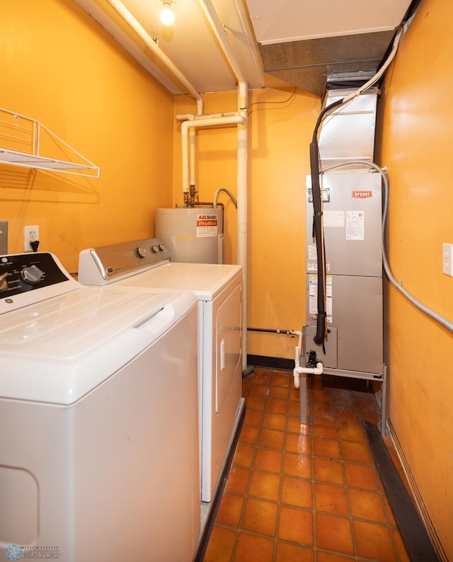 laundry area with dark tile patterned flooring, heating unit, washing machine and dryer, and gas water heater