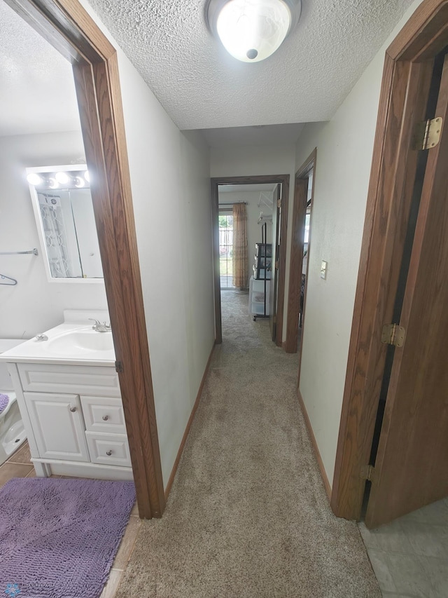 hallway featuring light tile patterned flooring, sink, and a textured ceiling