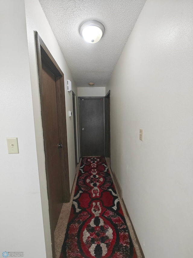 hall with carpet floors and a textured ceiling