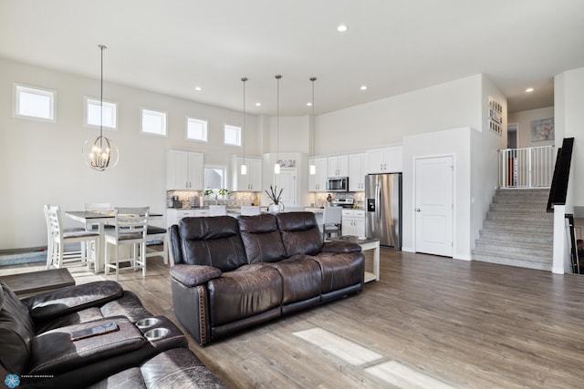 living room with a towering ceiling, a notable chandelier, and light wood-type flooring