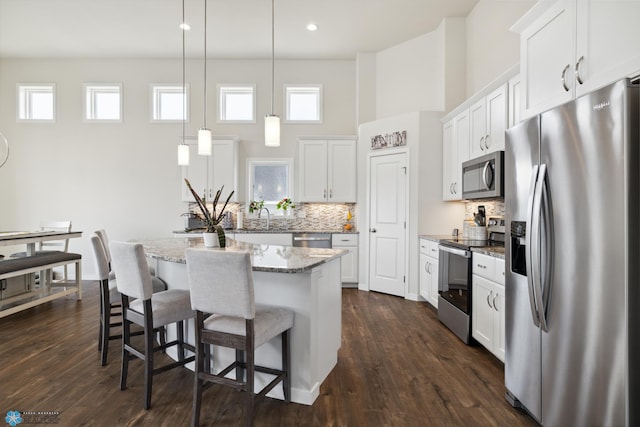 kitchen featuring dark hardwood / wood-style floors, hanging light fixtures, appliances with stainless steel finishes, and a kitchen island