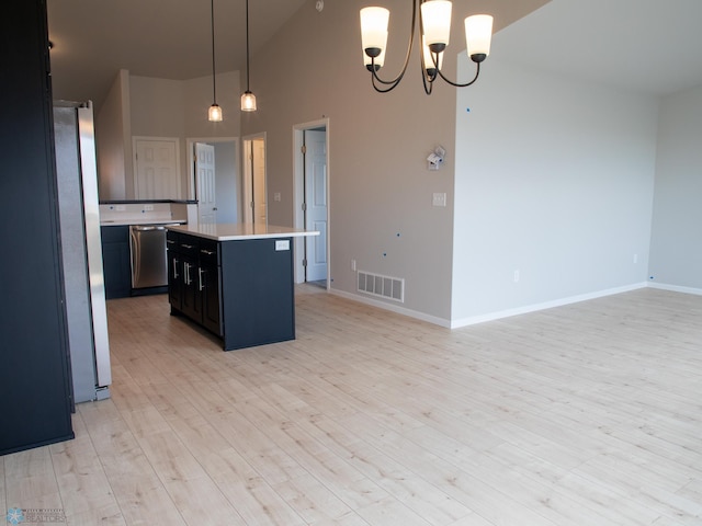 kitchen with decorative light fixtures, high vaulted ceiling, a kitchen island, appliances with stainless steel finishes, and light hardwood / wood-style flooring