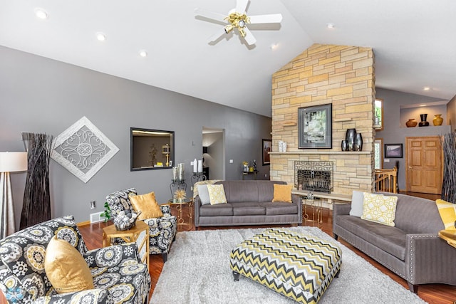 living room featuring a stone fireplace, hardwood / wood-style flooring, vaulted ceiling, and ceiling fan