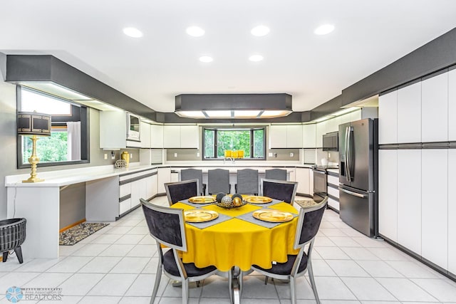 kitchen featuring light tile patterned flooring, stainless steel appliances, and white cabinets