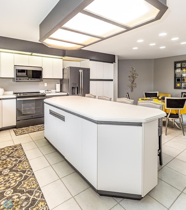 kitchen featuring a center island, appliances with stainless steel finishes, white cabinets, and light tile patterned floors