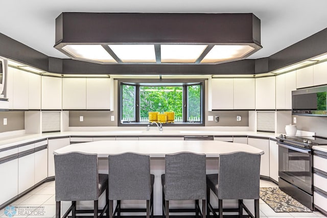 kitchen featuring white cabinetry, light tile patterned floors, a center island, black range with electric cooktop, and sink