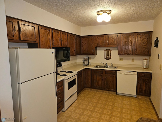 kitchen featuring sink, a textured ceiling, white appliances, and light tile patterned floors