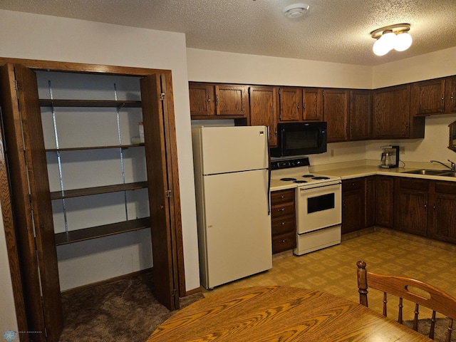 kitchen with light tile patterned flooring, sink, a textured ceiling, and white appliances