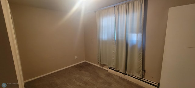 carpeted empty room featuring baseboard heating