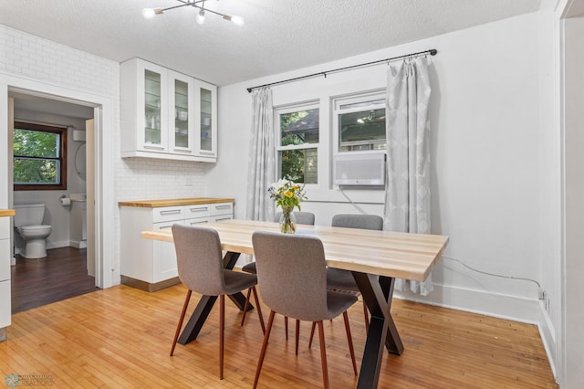 dining room featuring light hardwood / wood-style floors, a textured ceiling, plenty of natural light, and cooling unit