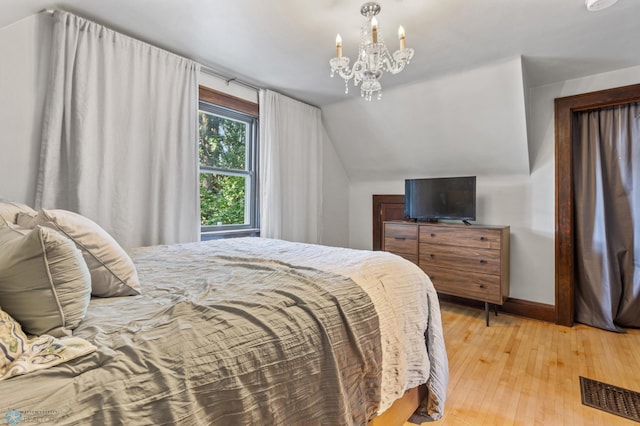 bedroom with lofted ceiling, a notable chandelier, and light hardwood / wood-style flooring