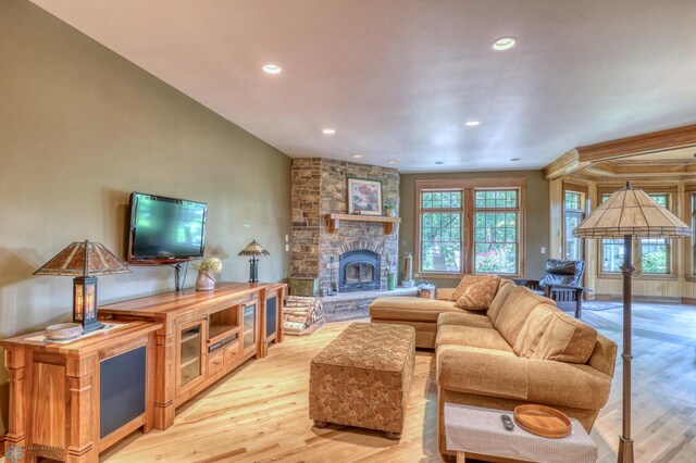 living room with a fireplace, lofted ceiling, and light hardwood / wood-style flooring