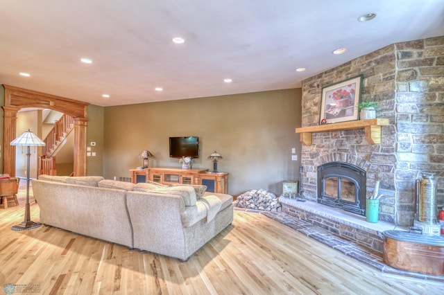 living room with a stone fireplace and light hardwood / wood-style floors