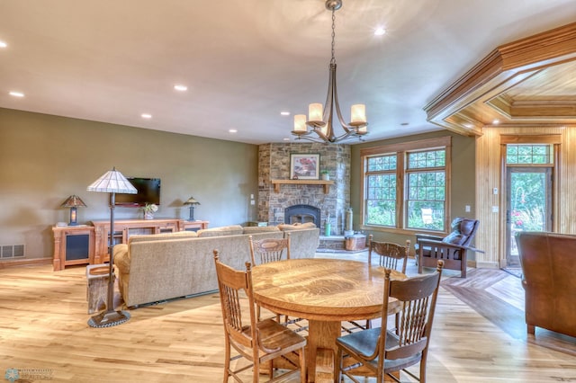 dining space with light hardwood / wood-style flooring, an inviting chandelier, and a fireplace