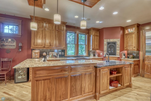 kitchen featuring light wood-type flooring, decorative backsplash, and an island with sink