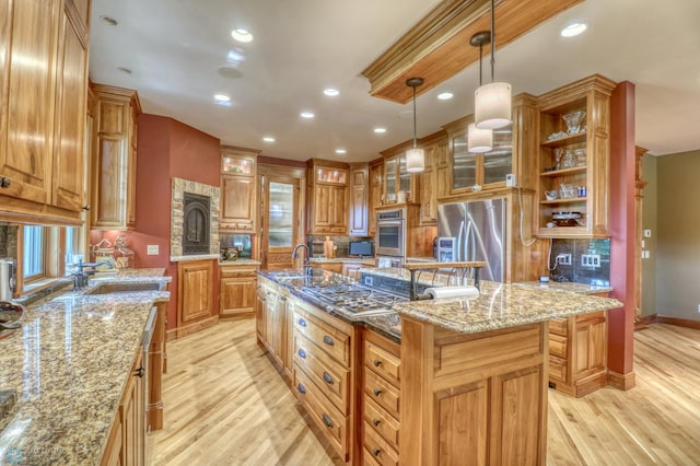 kitchen featuring appliances with stainless steel finishes, light wood-type flooring, light stone countertops, and an island with sink